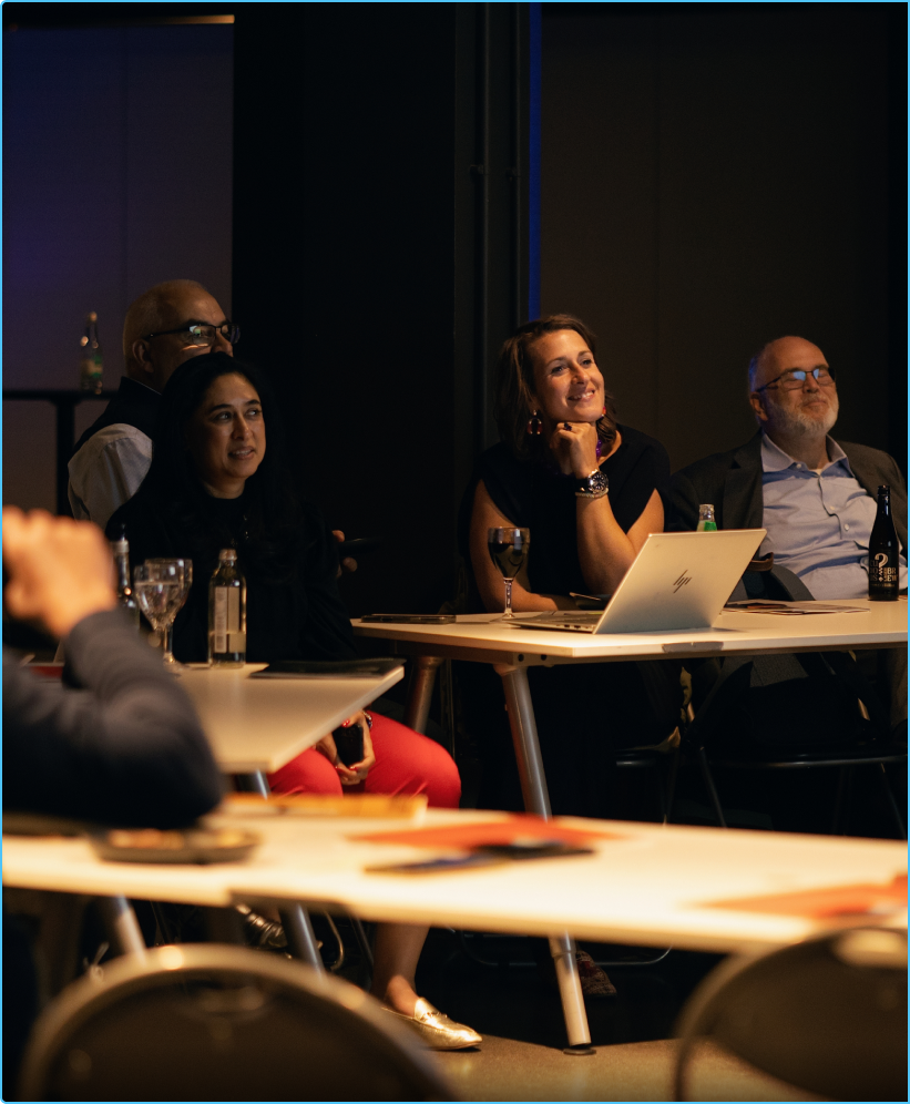 A team seated at tables during the debrief, discussing their results