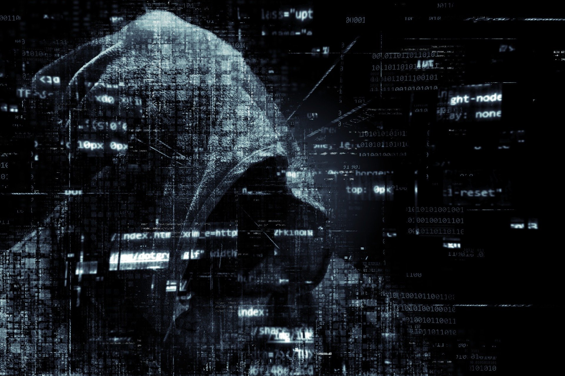A hooded hacker in front of computer coding