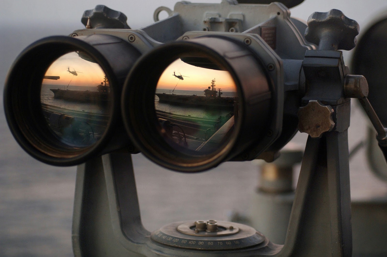 Binoculars spying on a military ship and helicopter