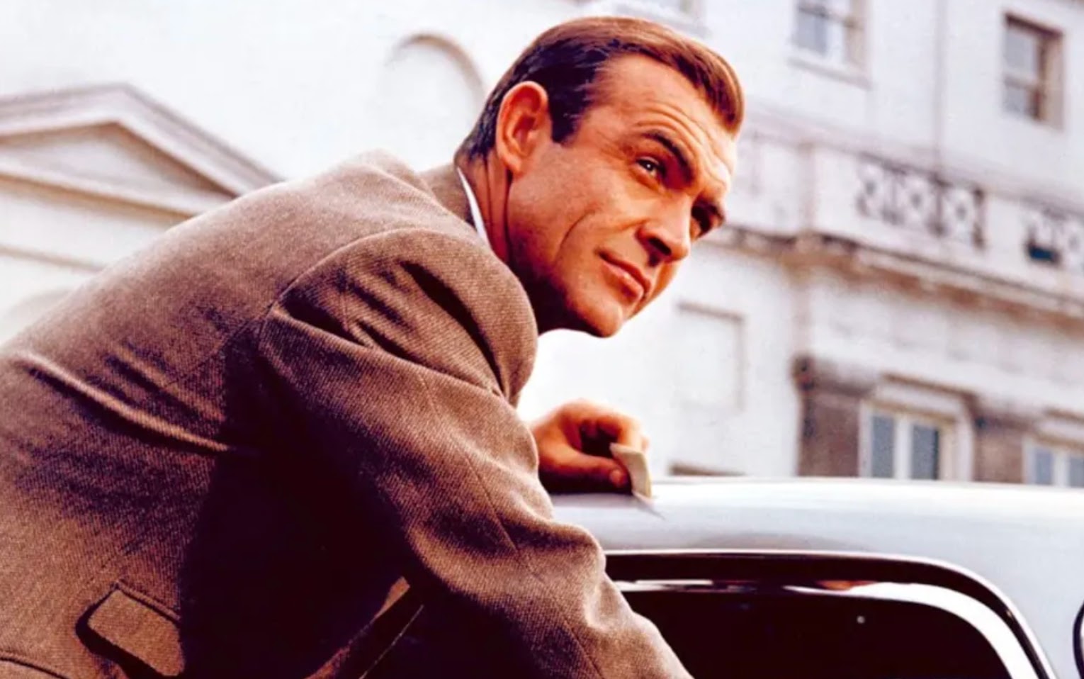 James Bond actor Sean Connery leans against his Goldfinger DB5 Aston Martin